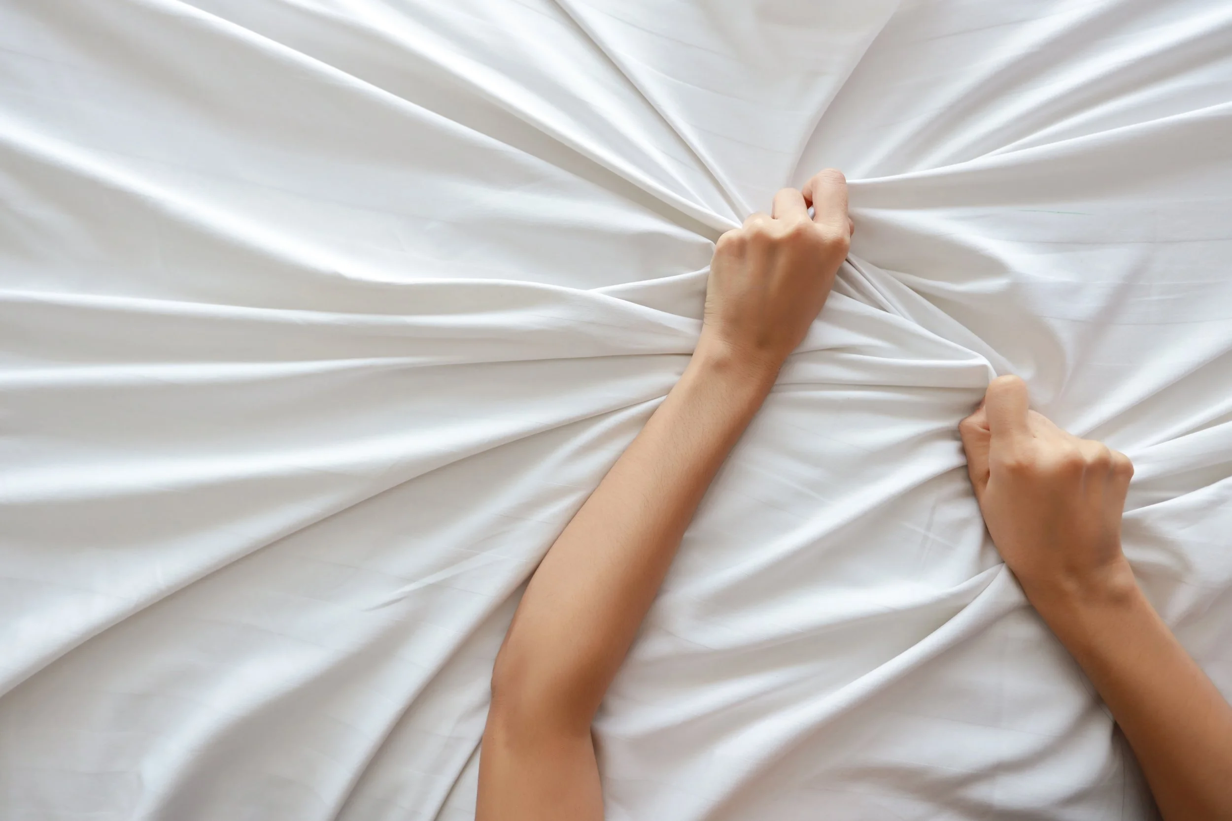 person grabbing sheets having an orgasm