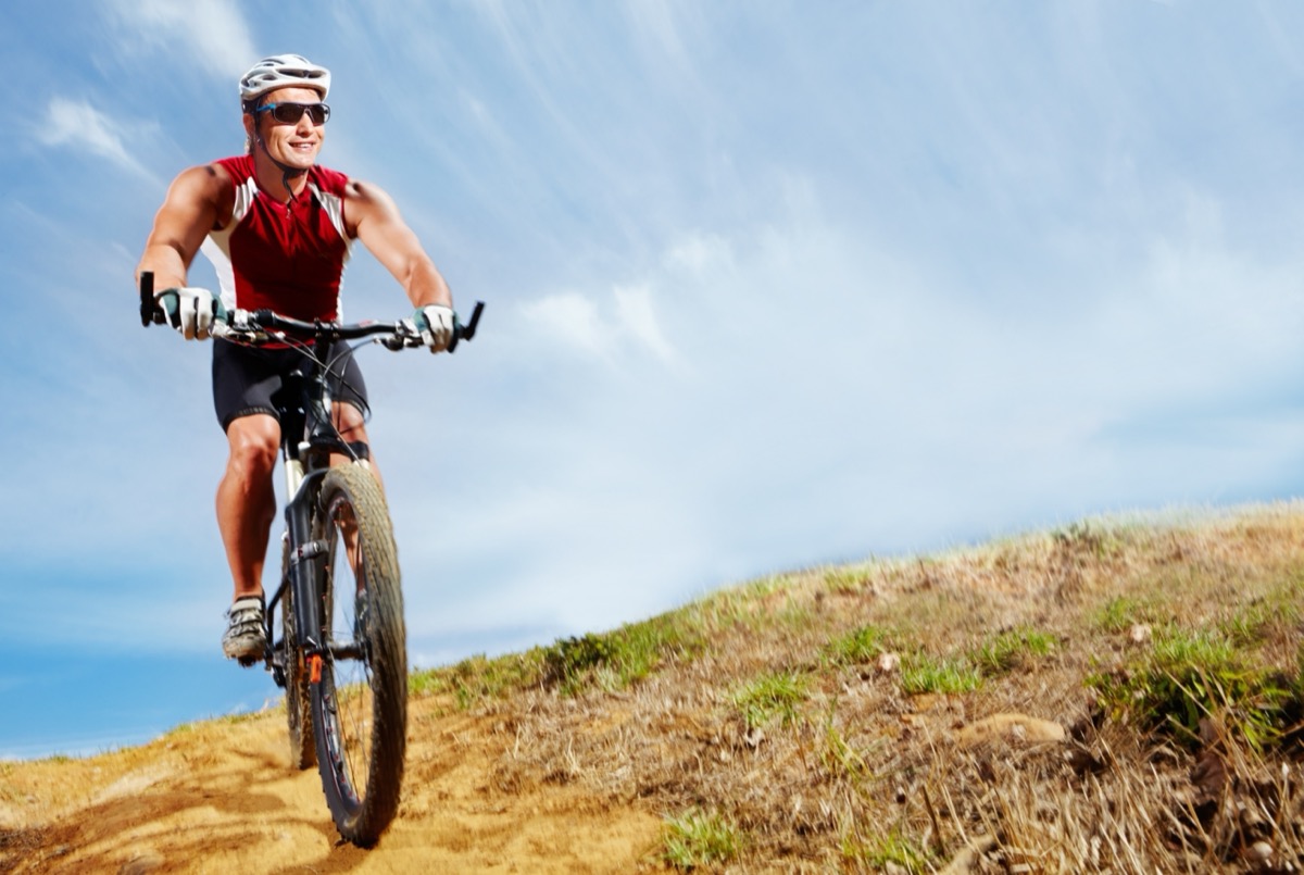 Male mountain biker riding uphill on a dirt trail